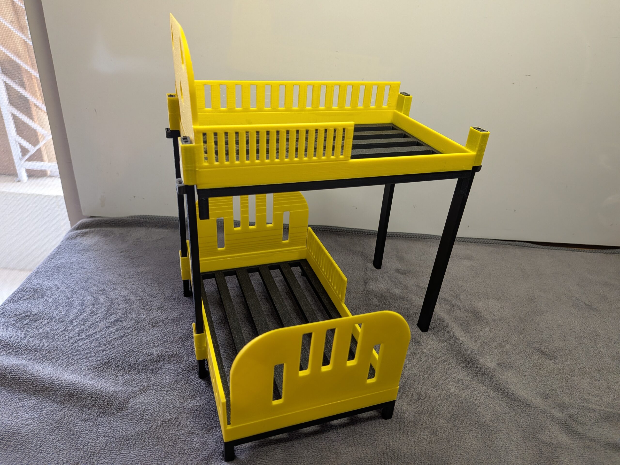 Modern 1:12 scale 3D printed stackable bunk beds for dollhouses in bright yellow with black frames and slatted bases.